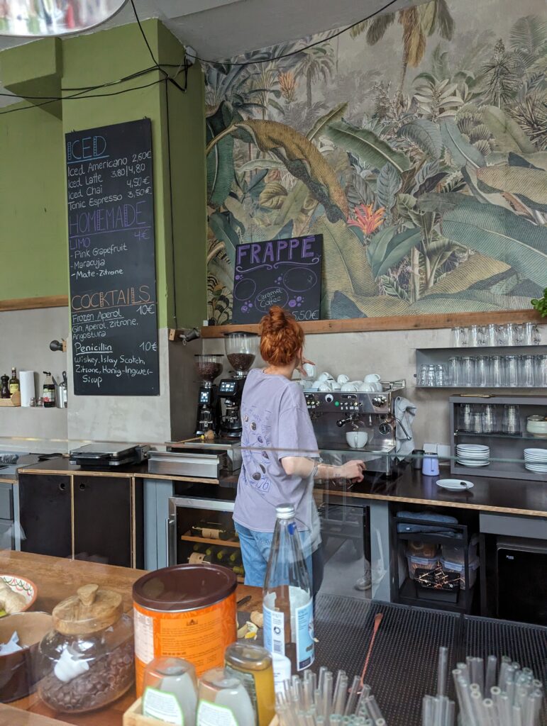 Theke des Cafés: Frau steht an einer Kaffeemaschine